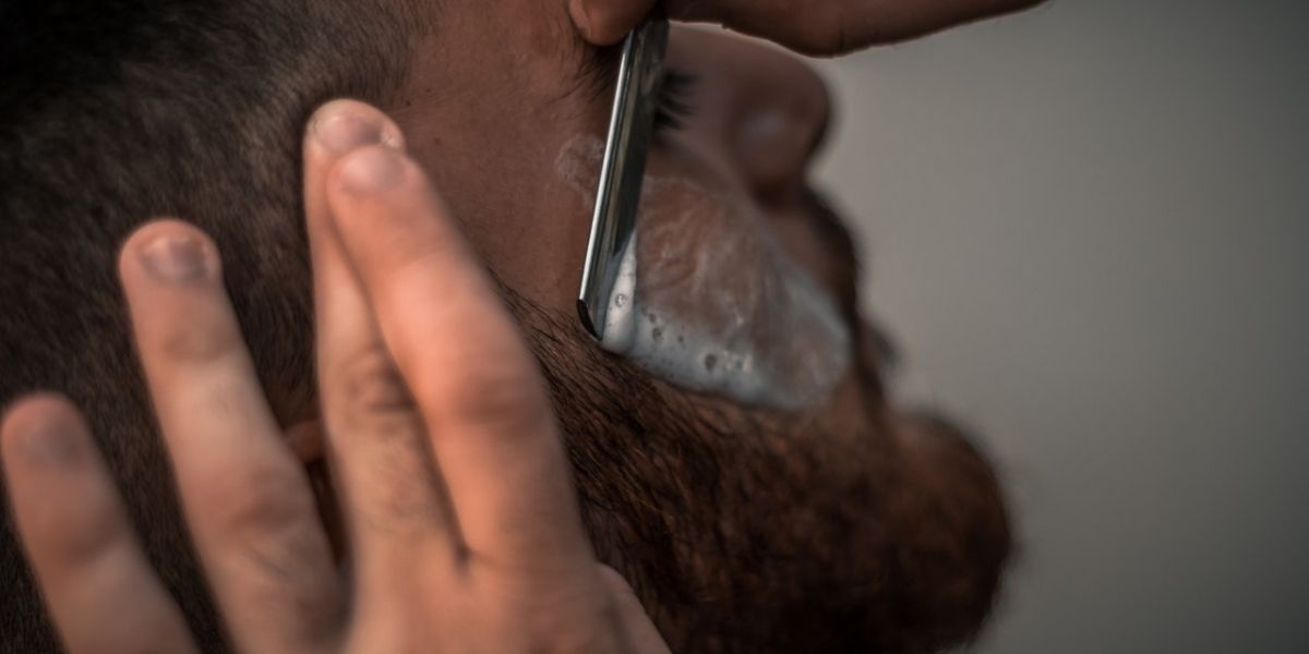 man with red beard getting a straight razor shave