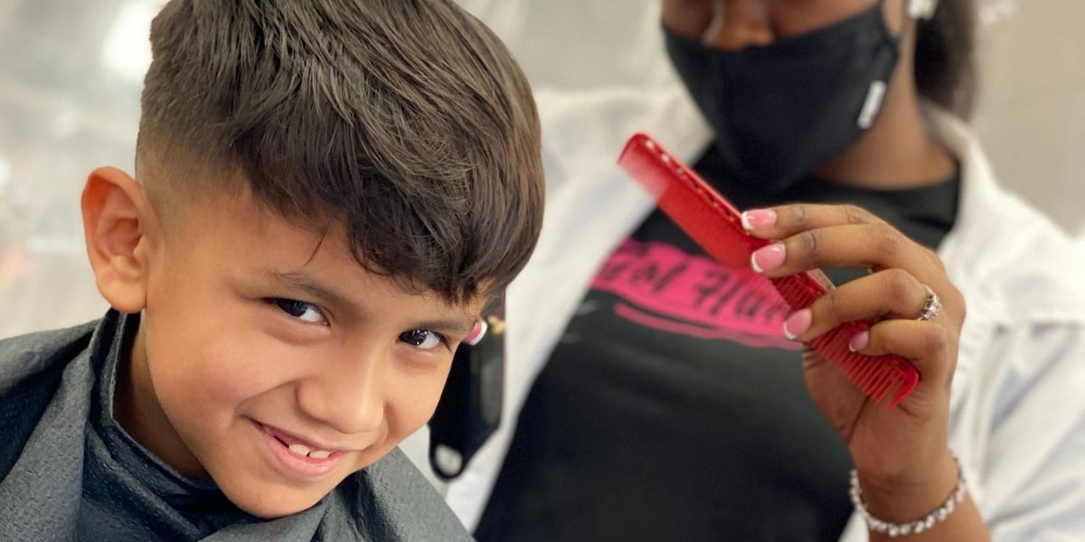 little boy smiling while getting a hair cut